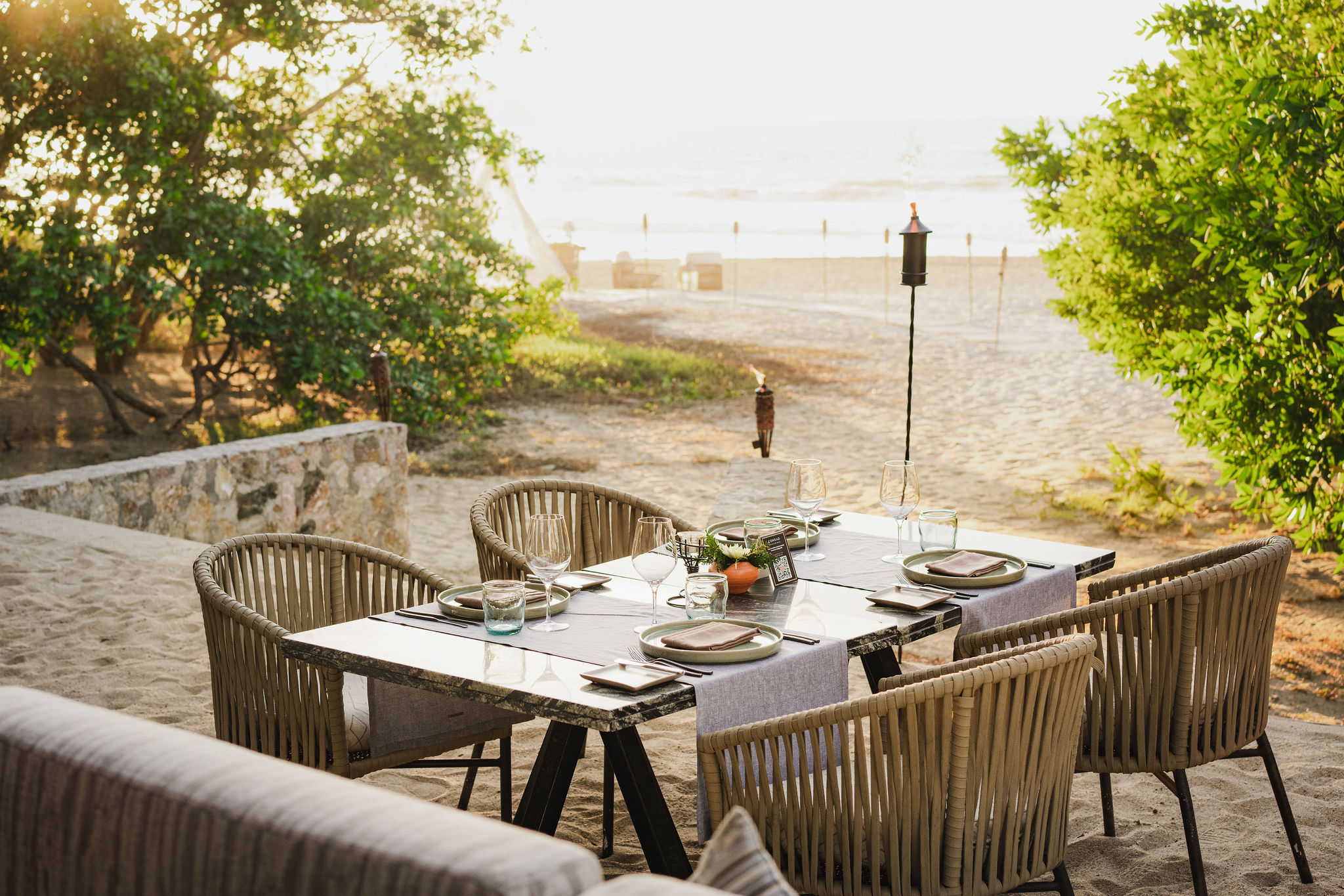 picture of the dining table with chairs on the beach with the sea view